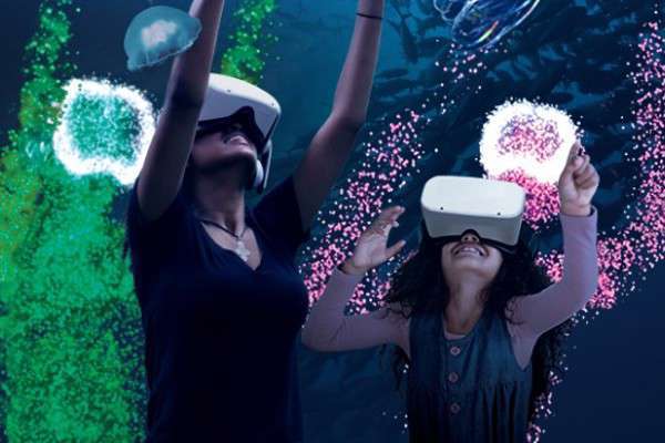 Two people using VR goggles in front of neon sea scene